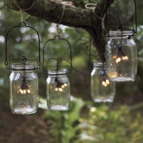 Bocaux avec des LED suspendus dans un jardin.